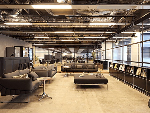 黒や茶色をベースにした木目調の室内で、休憩スペースには大きなソファや都心の風景を一望できる環境