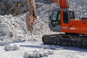 岩盤より切り出した石を、重機のノミで一つ一つ整形します。