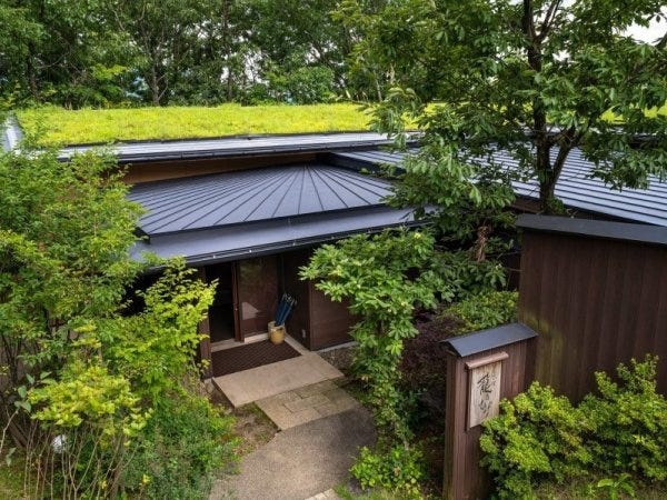 屋根に龍のひげを植えて、周囲の自然と調和した入り口。