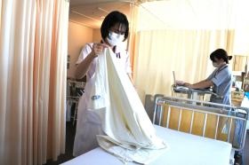 看護助手が入院患者さんのベッドシーツを取り替えています