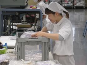 工場内にて白衣の梱包作業