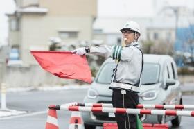 反対車線側の同僚と無線機や手旗で合図をして片側交互通行を行う