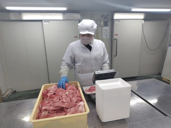 製造スタッフの作業風景です。お肉のグラム数を測り、パック詰めをしています。
