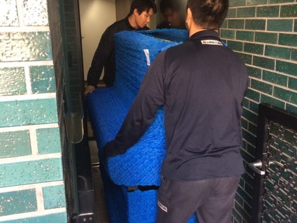 二人でピアノを運んでいる作業風景です。ぶつけないように丁寧に運びます。